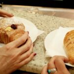 Persone che mangiano croissant al bar