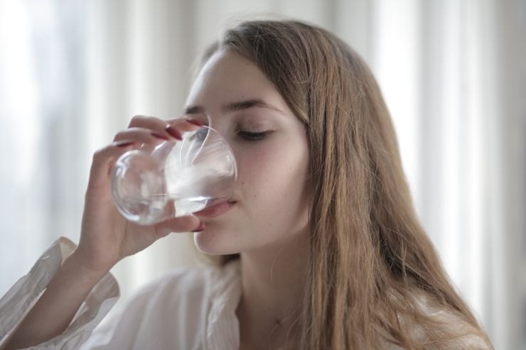 Donna beve bicchiere di acqua appena alzata