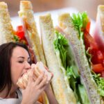 Dei sandwich freschi ed una donna che mangia