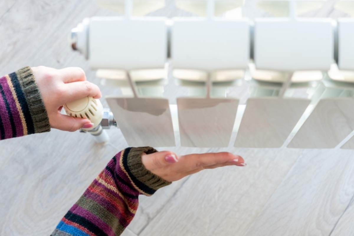 Mano femminile sul termosifone per controllare la temperatura 